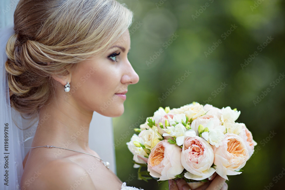 Obraz premium Beauty bride in bridal gown with bouquet and lace veil in the na