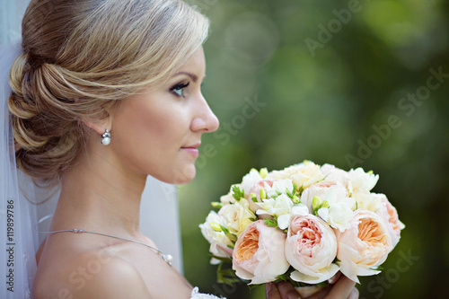 Beauty bride in bridal gown with bouquet and lace veil in the na