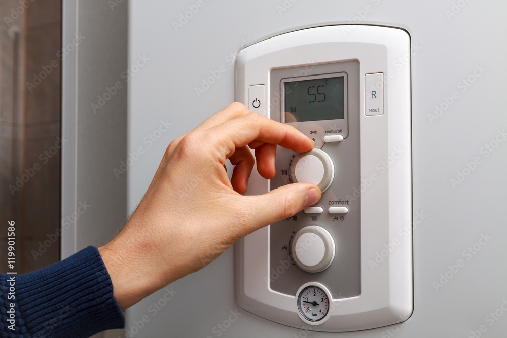 Men hand regulate temperature on 55 degree in control panel of central heating.