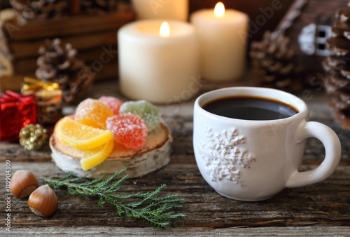 Cup of coffee, pine cones, burning candles and colorful candy