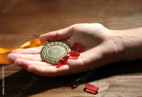 Female hand with pills and medal. Doping in sport concept