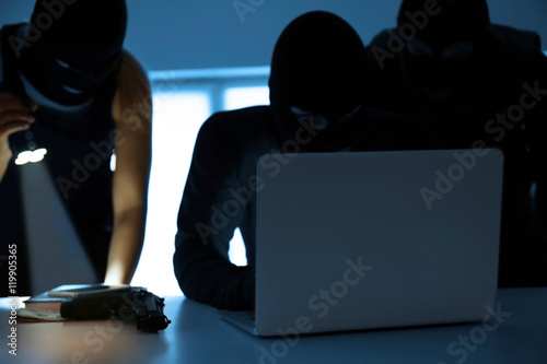 Vászonkép Armed thieves hacking laptop in the room