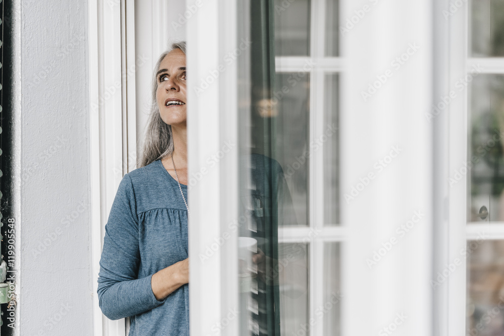 Woman standing at open terrace door looking up Woman standing at open terrace door looking up