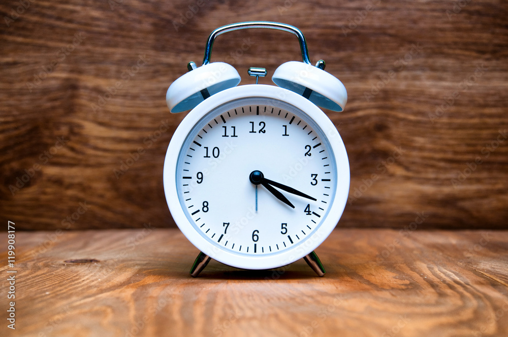 White alarm clock isolated on wooden background White alarm clock isolated on wooden background