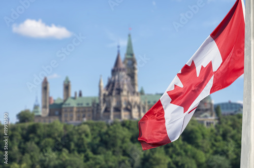 Canadian flag waving with Parliament Buildings hill and Library photo