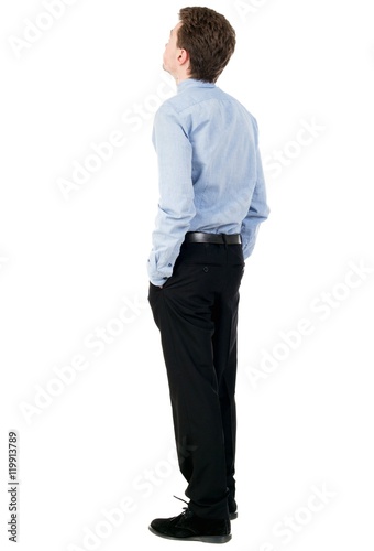back view of Business man looks. curly-haired businessman in light shirt stands with his hands in his trouser pockets. © ghoststone