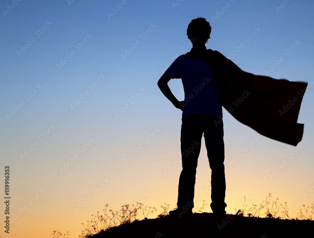 Boy playing superheroes on the sky background, silhouette of tee