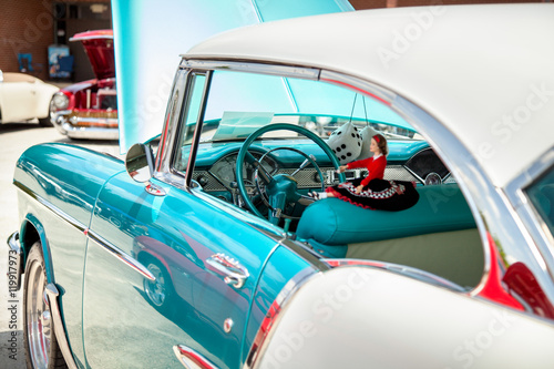 Side view of old American 70s customized muscle car blue color with the hood open on the show.