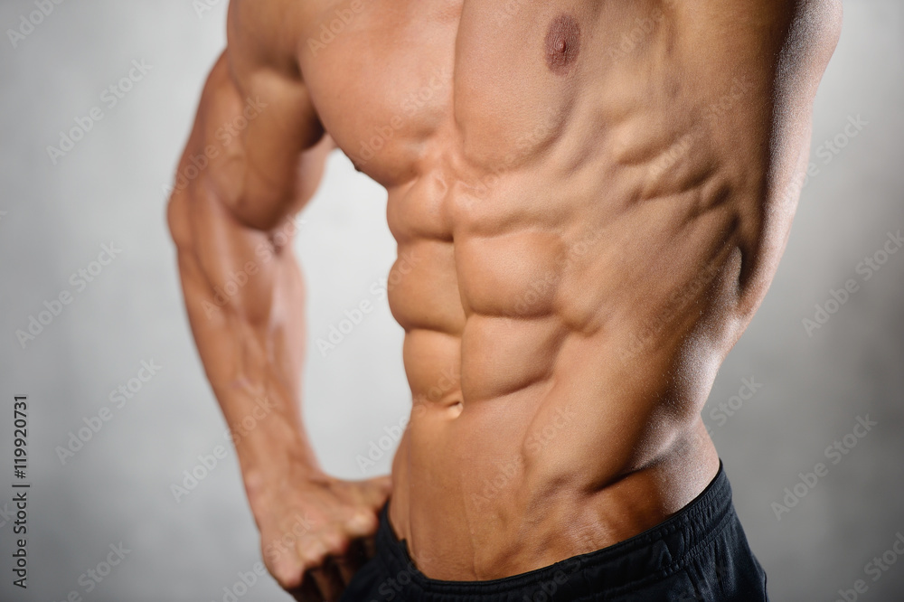 Strong athletic man fitness model showing six pack abs