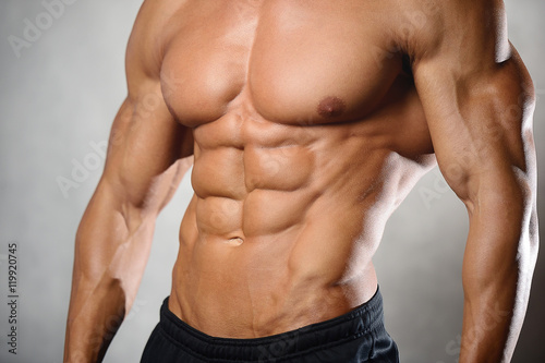 Strong athletic man fitness model showing six pack abs