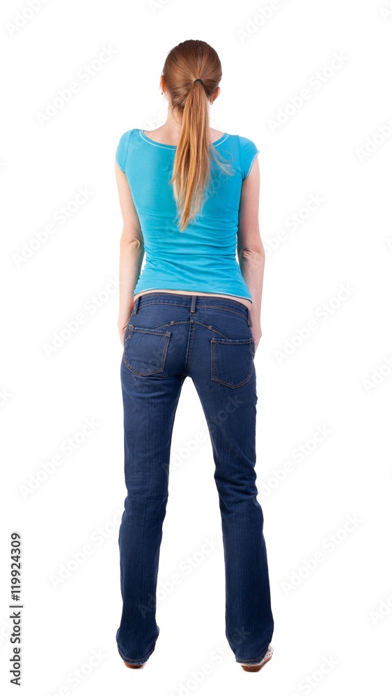 back view of standing young beautiful blonde woman in blue t-shirt and jeans. girl watching. Rear view people collection. backside view of person. she curiously looks up. Isolated over white back view of standing young beautiful blonde woman in blue t-shirt and jeans. girl watching. Rear view people collection. backside view of person. she curiously looks up. Isolated over white