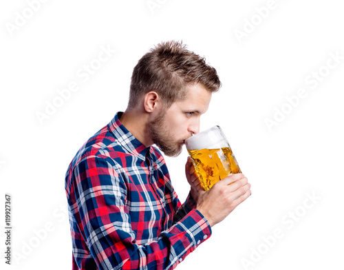 Hipster man in checked shirt drinking beer, studio shot