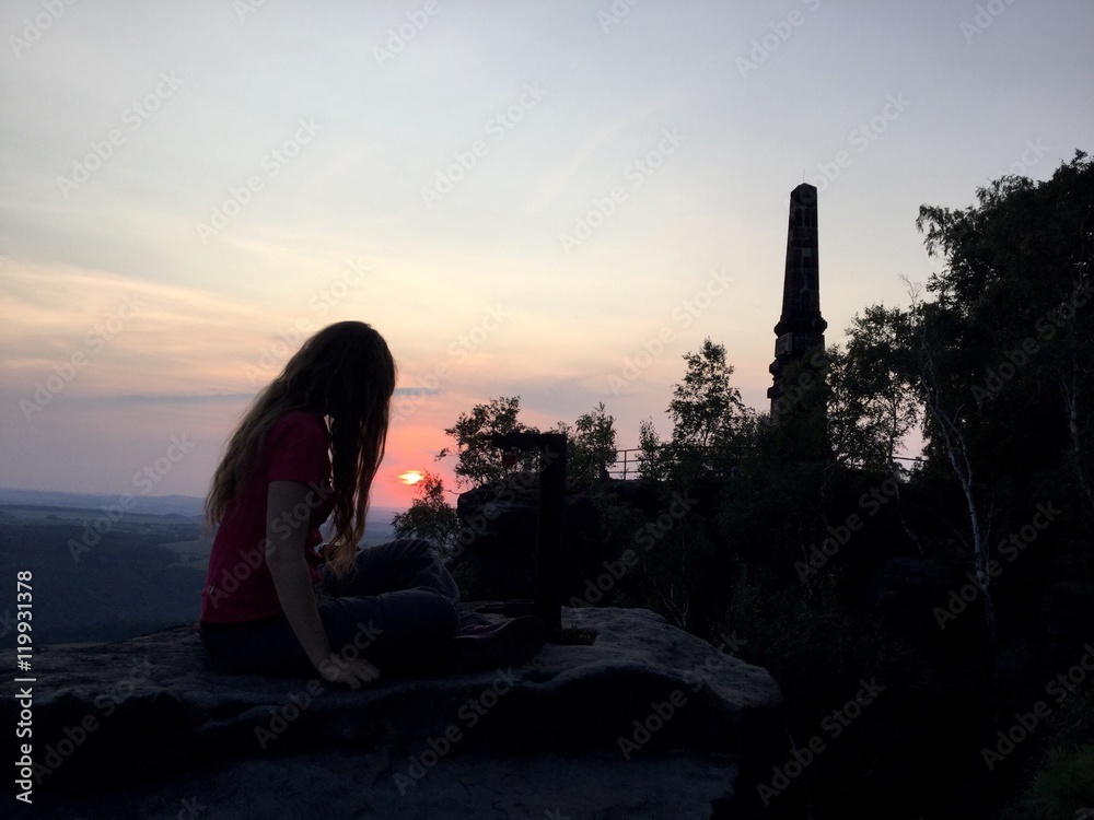 junge Frau auf Felsen im Sonnenuntergang
