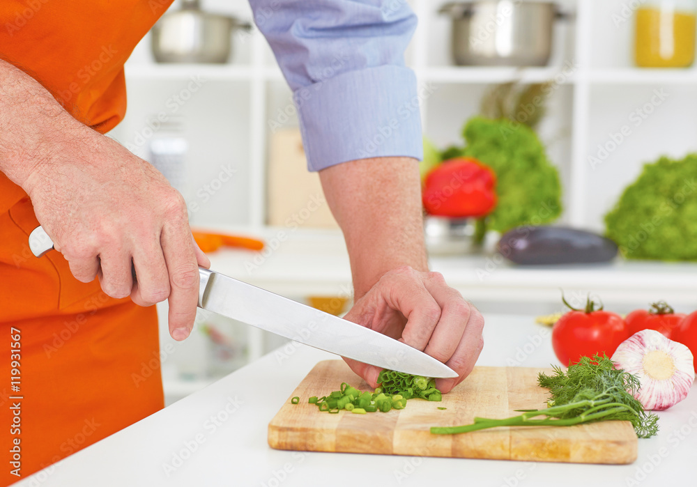 Mature man cutting vegetables in the kitchen.