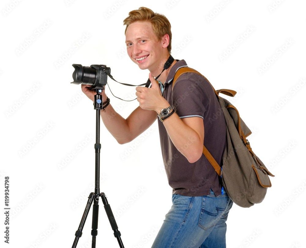 Young man traveler taking pictures by dslr camera on tripod isolated on white. Thumb up
