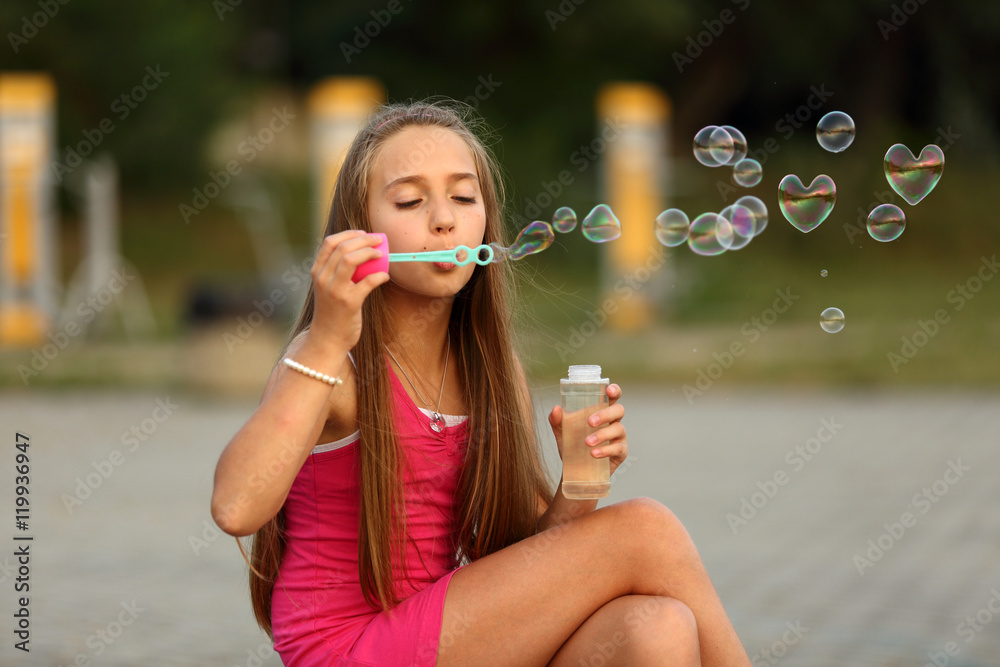 Śliczna dziewczynka puszcza bańki mydlane, serca. Stock Photo | Adobe Stock
