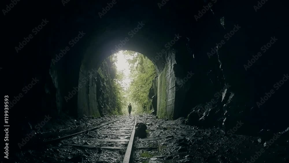 Woman getting into  the darkness over the rails of an abandoned train in inside of the ecuadorian jungle