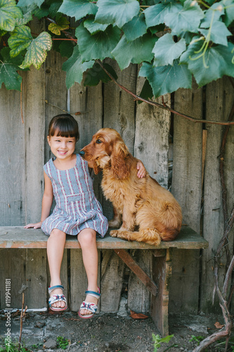 country girl sitting on a bench with her dog under vine. wooden