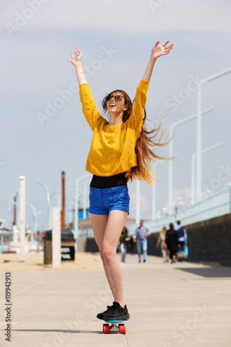 Woman riding skateboard with hands outstretched