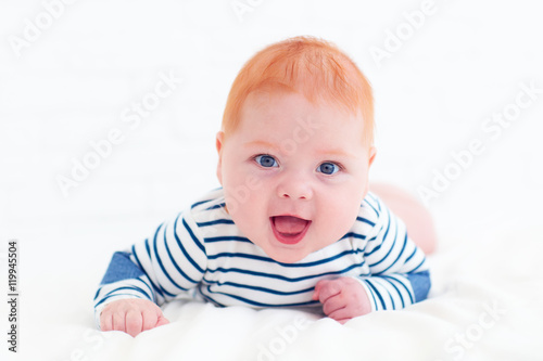 portrait of happy redhead baby boy lying on belly