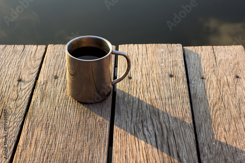 Thermo cup with coffee on old wooden pier.