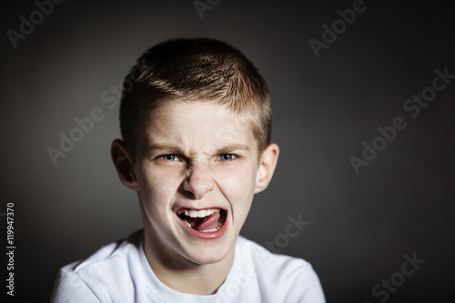 Solitary boy making faces against black background