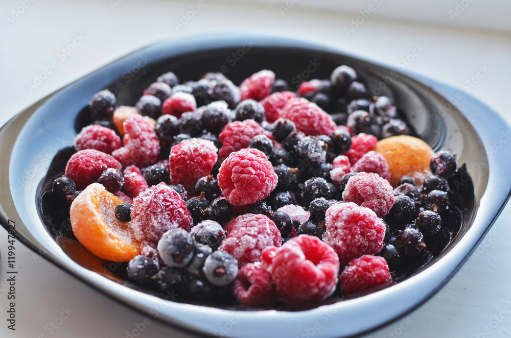 A plate of fresh frozen berries including raspberry, black current, and apricots A plate of fresh frozen berries including raspberry, black current, and apricots
