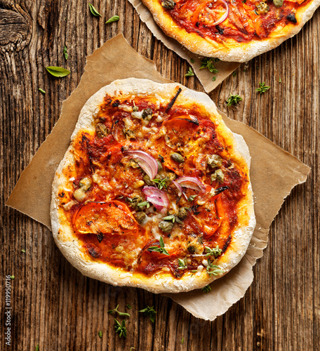 Фотография Small homemade vegetarian  pizza with addition of tomatoes, capers,onion, cheese