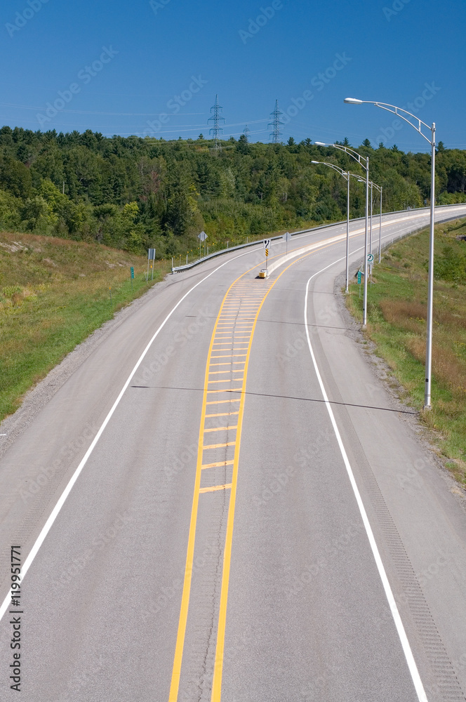 Curve on a Major Highway with Streetlamps and Blue Sky