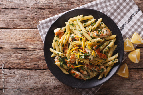 Penne Pasta with pesto, chicken breast and lemon closeup. Horizontal top view
