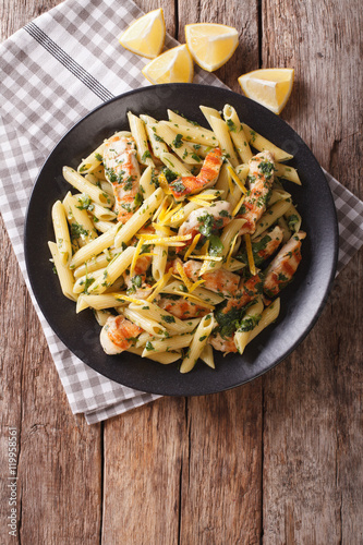 Penne Pasta with pesto, chicken breast and lemon closeup. Vertical top view 