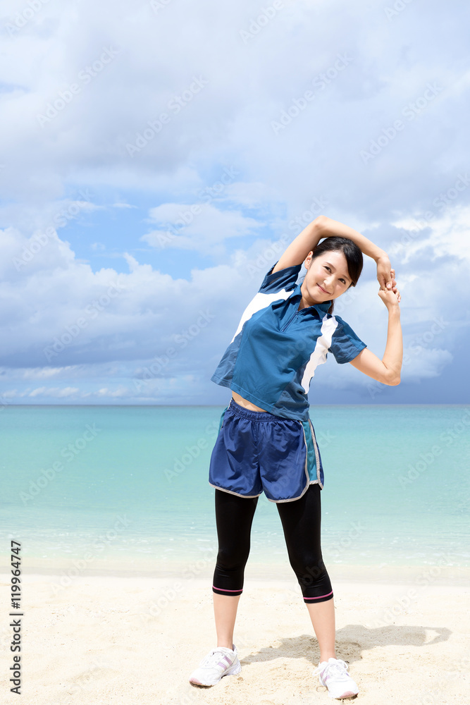 南国の美しいビーチでストレッチをする女性