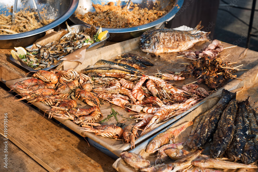 Seafood barbecue outdoors. Grilled shrimp and fish, street food mediterranean cuisine.
