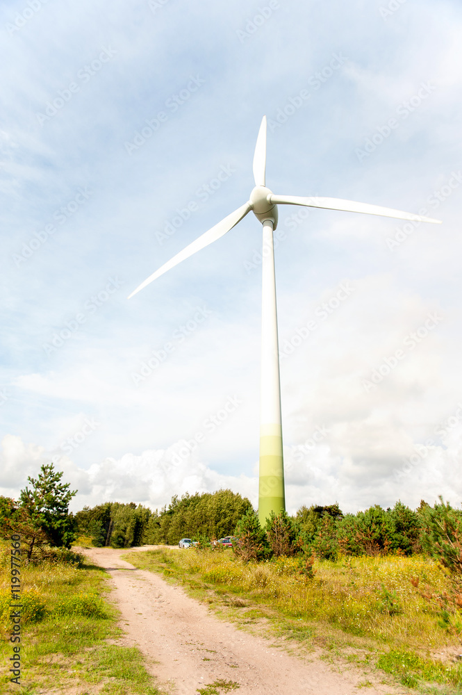 Fototapeta premium Energy generator wind turbine on dramatic cloudy blue sky backgr