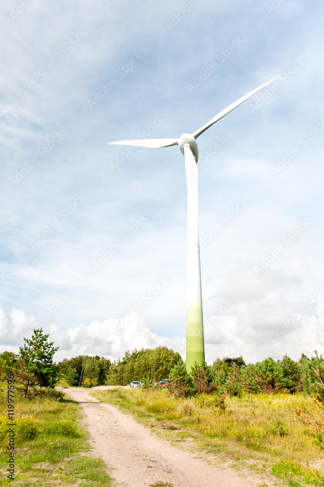Fototapeta premium Energy generator wind turbine on dramatic cloudy blue sky backgr