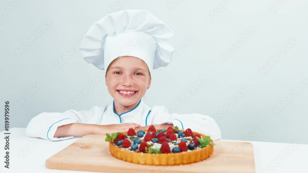 Close up portrait young baker examines and touching using finger chocolate cake with sweets and fruits. Isolated on white Close up portrait young baker examines and touching using finger chocolate cake with sweets and fruits. Isolated on white