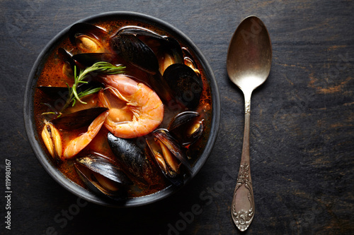 Bouillabaisse soup. Fish stew with mussels, shrimp, tomato and lobster. Traditional dish in France and Spain. Dark rustic style. Flat lay.