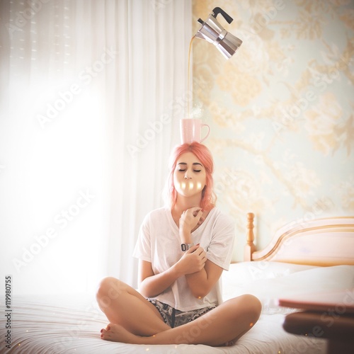 Woman on bed with cup of tea or coffee on head photo