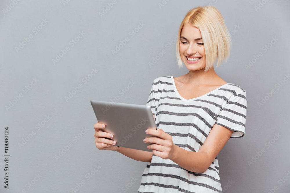 Smiling cute young woman with blonde hair using tablet Smiling cute young woman with blonde hair using tablet