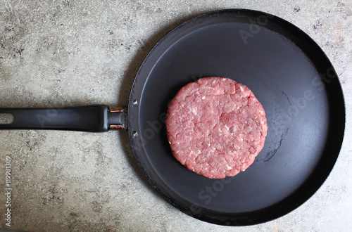 Crude cutlet of fresh meat, preparation for the burger on an old vintage pan. Food and Cooking. Selective focus with shallow depth of field