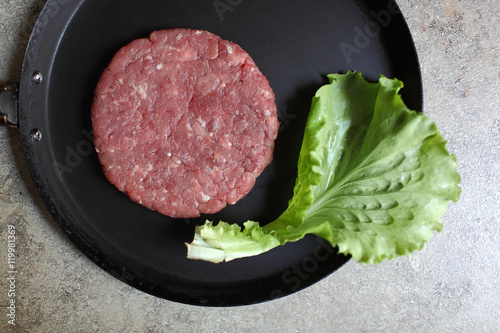 Crude cutlet of fresh meat, preparation for the burger on an old vintage pan. Food and Cooking. Selective focus with shallow depth of field