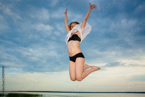 girl jumping on the beach at sunset background. Happy girl jumping on the beach on the dawn time. The concept of freedom and joy