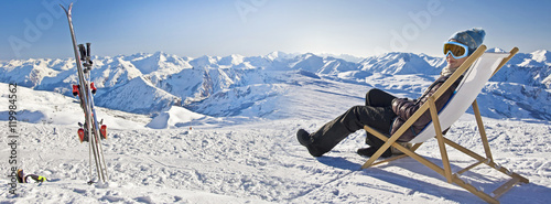 Photo Panorama of a girl sunbathing in a deckchair near a snowy ski slope