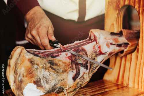 Man cutting spanish iberian ham. Close up detail.
