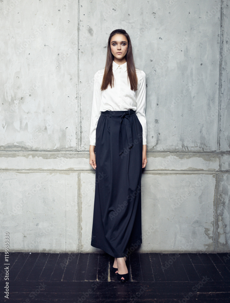 Fashion model wearing white shirt and long black skirt posing in studio  Stock Photo | Adobe Stock