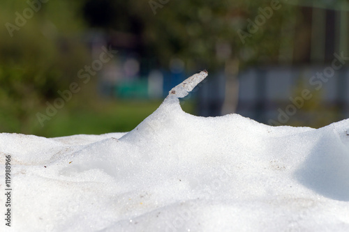 Large pile of dirty snow (ice) lies in the summer on the road an