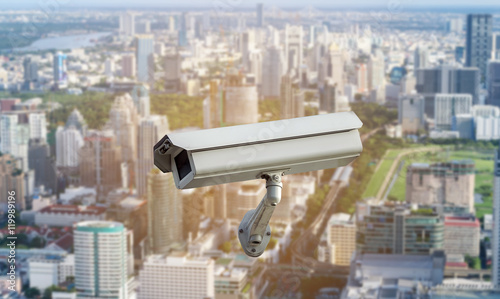 CCTV security camera isolated on blurred cityscape background.