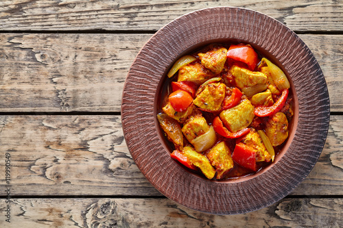 Chicken jalfrezi Indian restaurant menu fried spicy curry chilli meat and vegetables healthy dietetic asian food in clay dish on vintage table background.