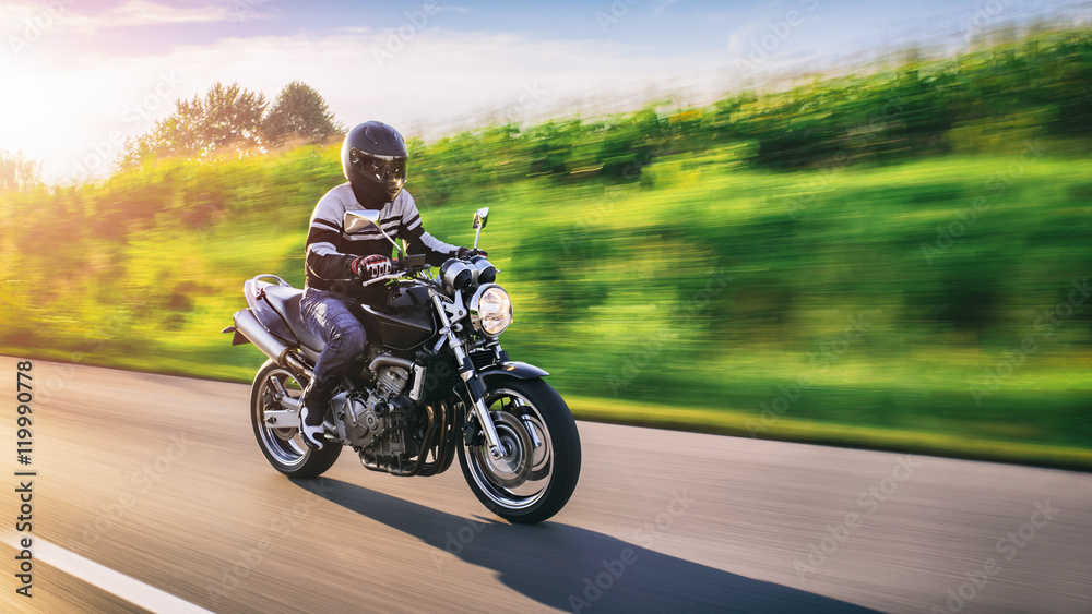 Man riding on a motorcycle, big movement of speed on the image, sunset in the background