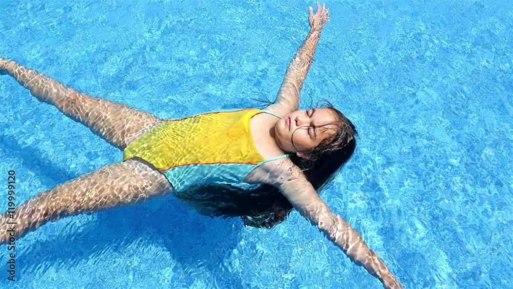 Little girl in swimsuit lying on the water in pool Stock Video | Adobe ...